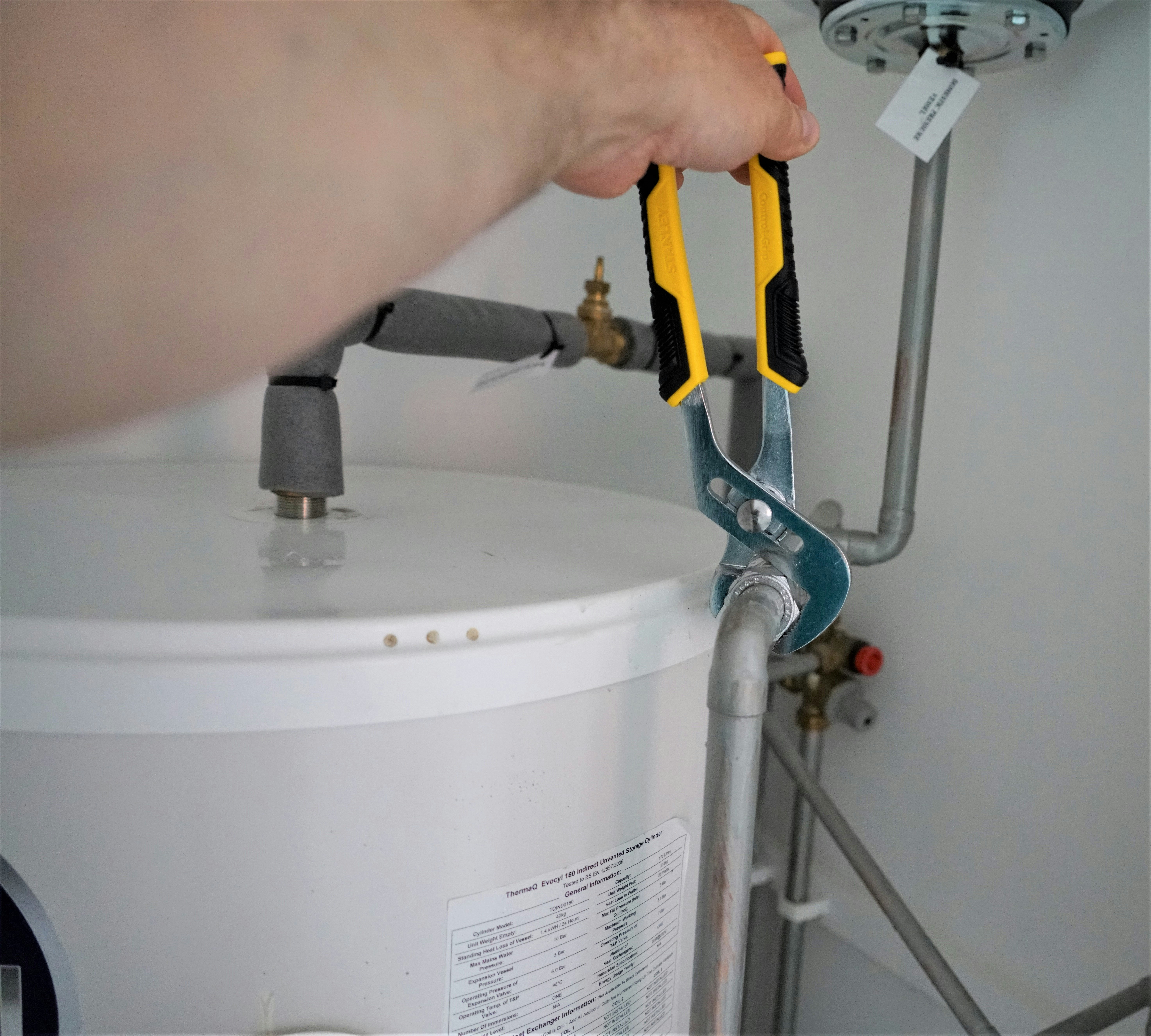 Person using a pipe wrench to work on a residential water heater