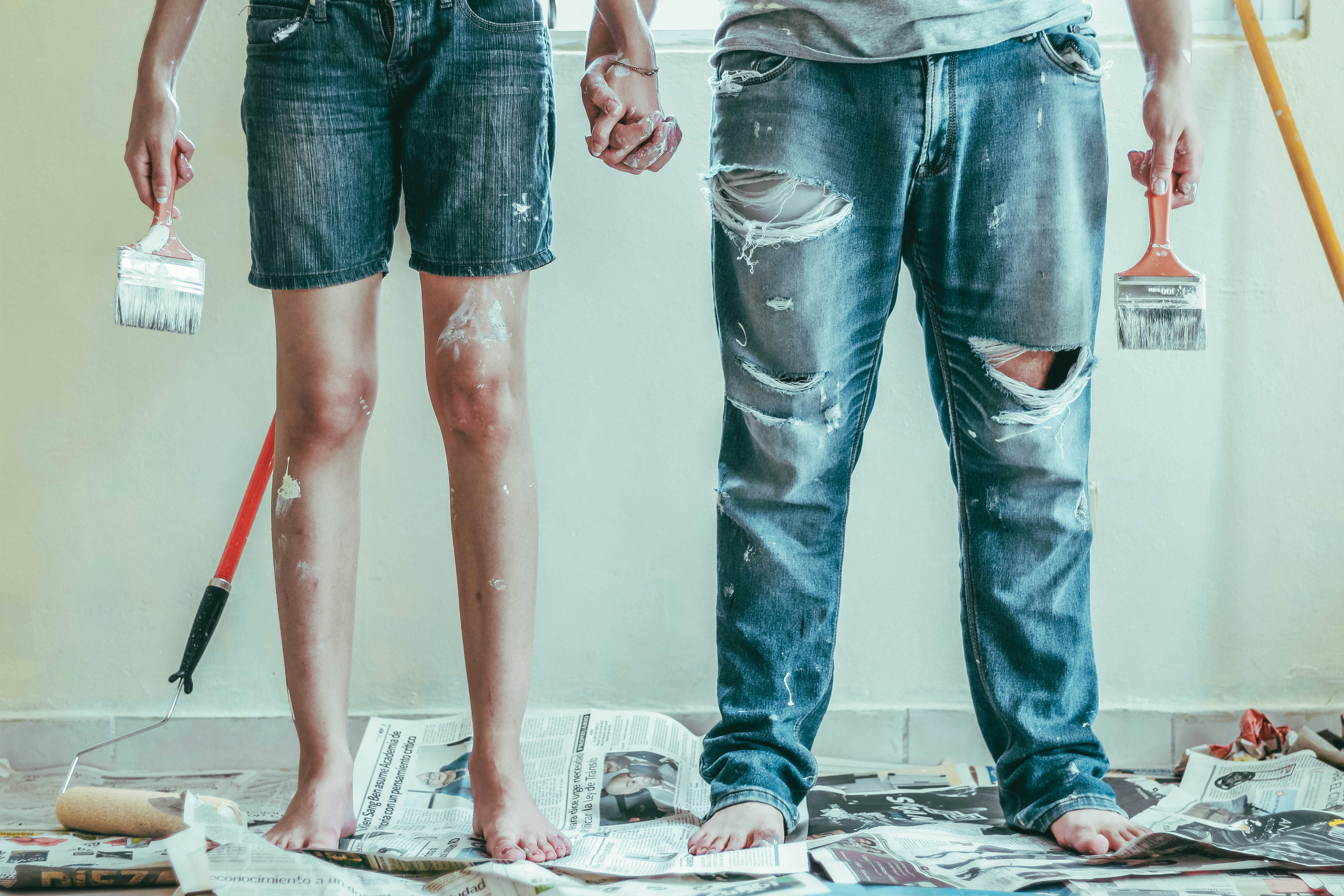 Two homeowners holding paintbrushes during a home renovation